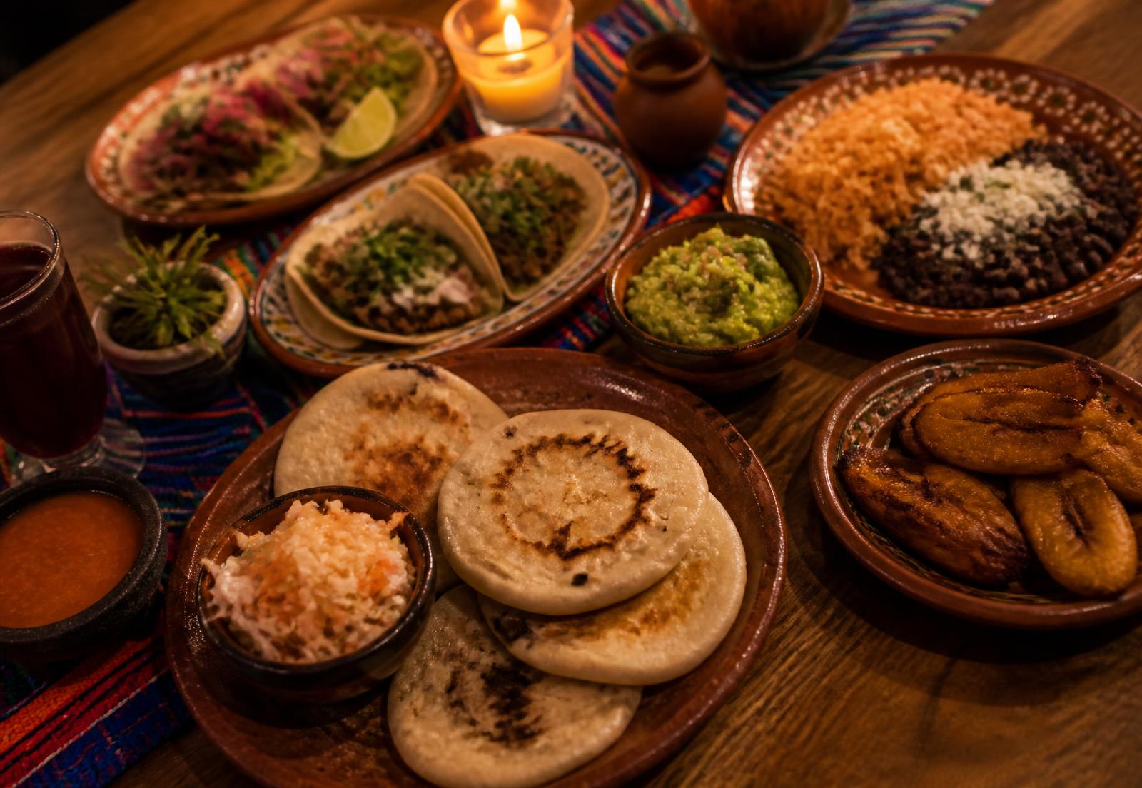 Table garnie de pupusas, tacos, guacamole, riz, haricots et plantains frits